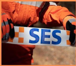 SES volunteer in orange overalls holding SES barrier tape